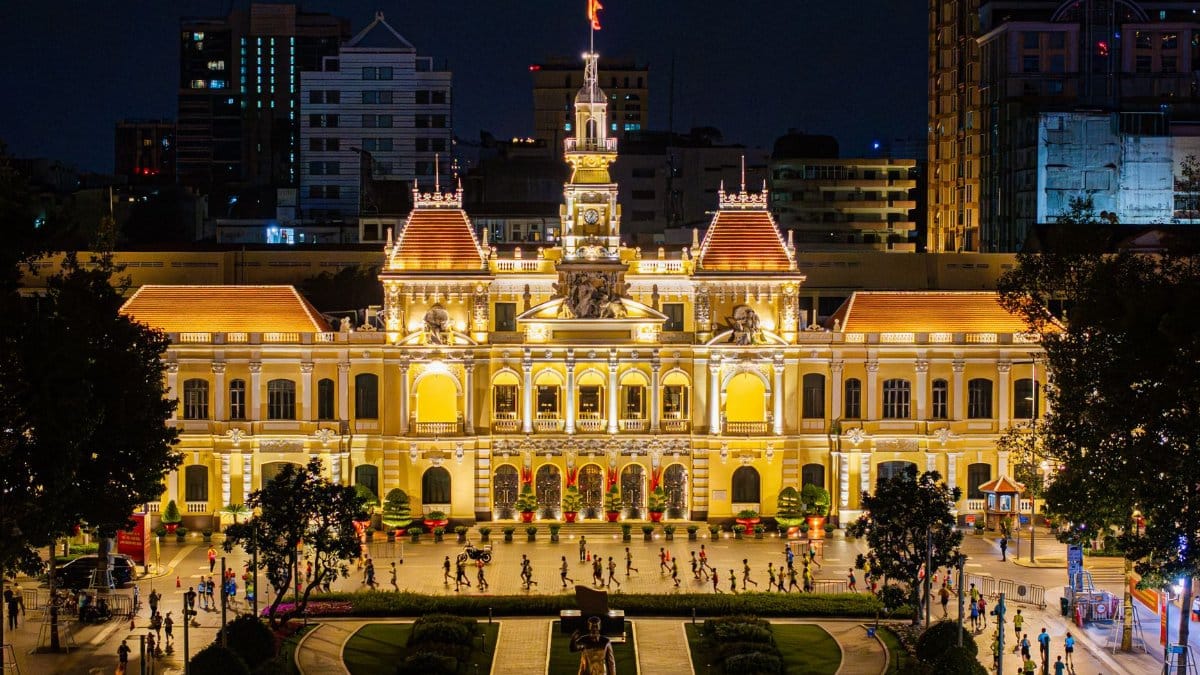 Vibrant night view of Ho Chi Minh City Hall with lively surroundings and illuminated architecture.