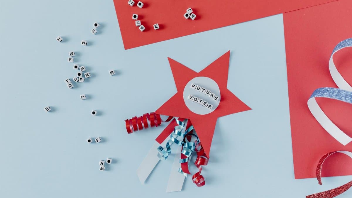 Flat lay of a red star with 'Future Voter' text, ribbons, and letter dice on a blue and red background.