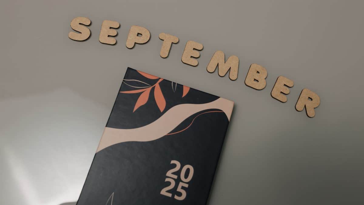 Flat lay of a 2025 calendar with September in wooden letters and an autumn design on a neutral background.