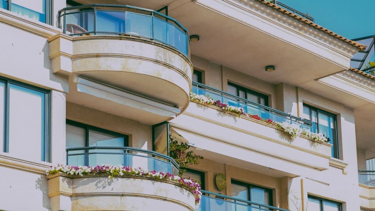 Stylish architecture featuring glass balconies and flower decorations on a sunny day.