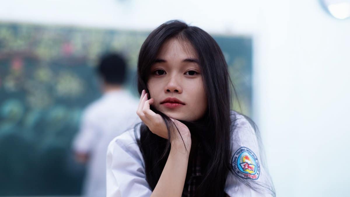 Young woman in a school uniform with a thoughtful expression in classroom setting.