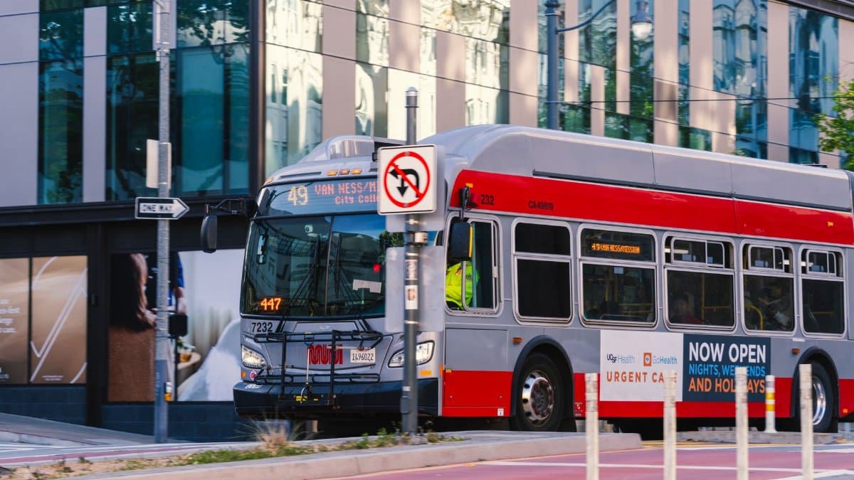 A San Francisco Muni bus traveling on Van Ness Avenue during the day in the cityscape.