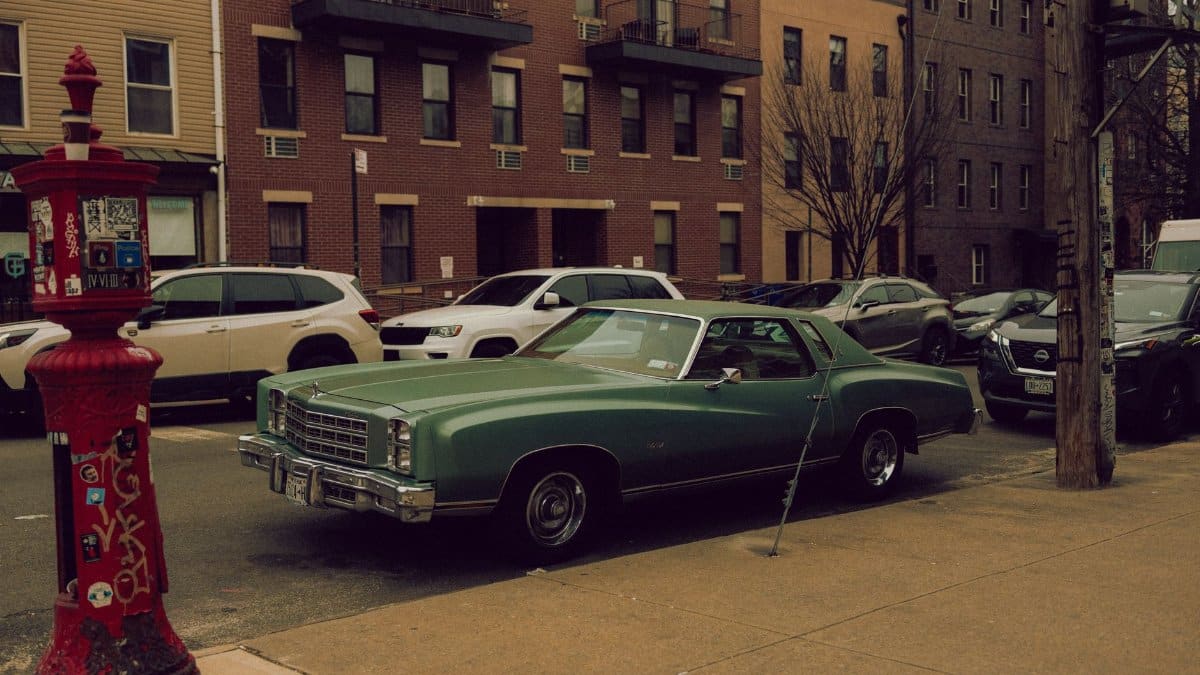A classic Chevrolet muscle car parked on a city street amidst urban architecture.