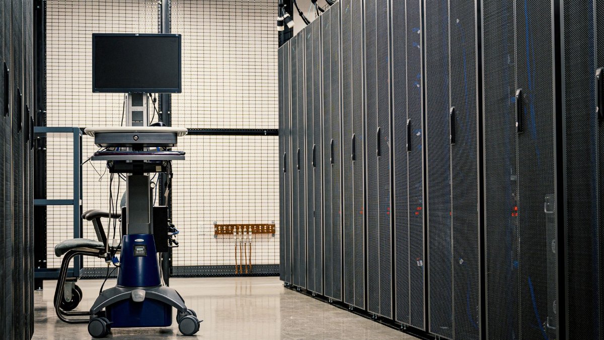 Contemporary computer on support between telecommunication racks and cabinets in modern data center