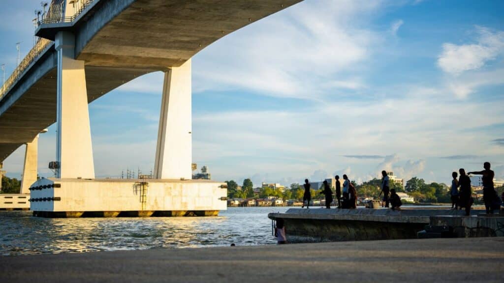 Children swimming and playing under the Marcelo Fernan Bridge at sunset in Mandaue, Philippines.