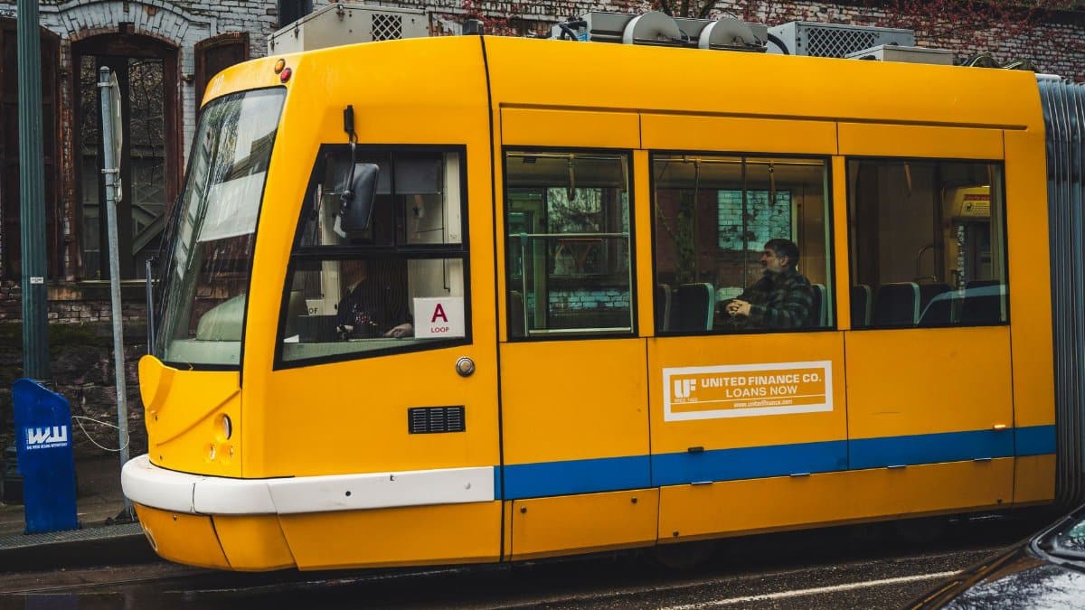 A bright yellow tram travels through the city streets, offering public transportation to passengers.