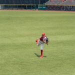A baseball player pitching on a grass field in an empty stadium.