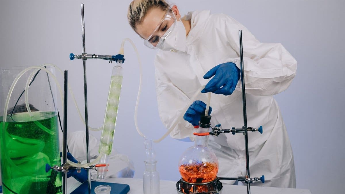 A scientist performs a chemical experiment in a laboratory wearing full protective gear, illustrating modern science.