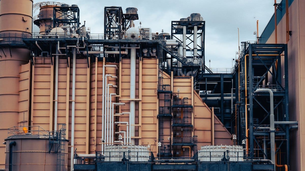 Detailed view of an industrial factory's exterior, showcasing machinery and structures under a cloudy sky.