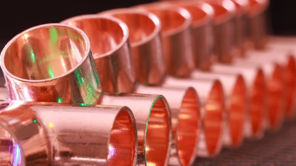 Copper plumbing fittings arranged in a row, showcasing metallic texture and industrial detail.