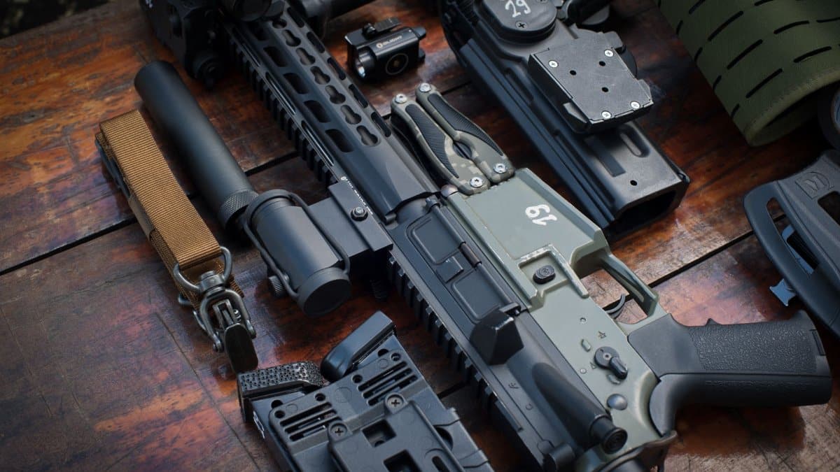 Close-up of tactical firearms and gear arranged on a rustic wooden surface.