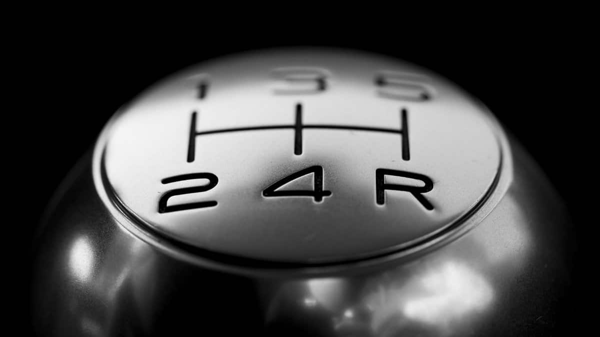 Detailed close-up of a stainless steel gear shift knob against a black background.