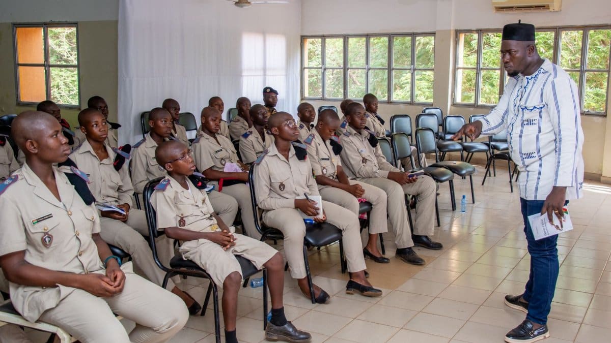A teacher engages with uniformed students in a classroom discussion, highlighting education and learning.