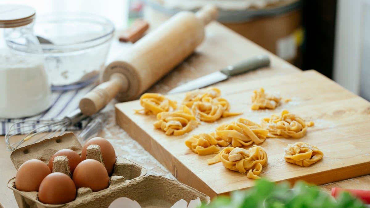 Kitchen counter with ingredients and homemade pasta nests on wooden cutting board before boiling