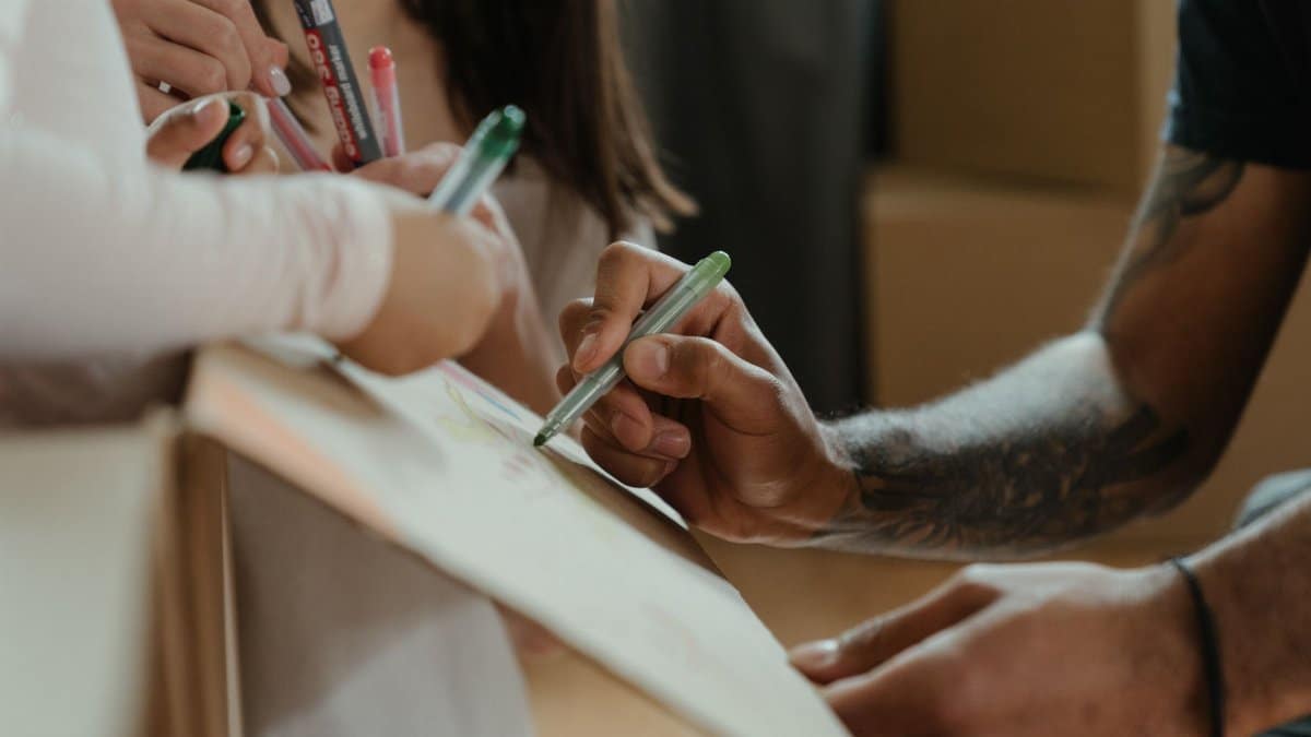 A family creatively decorates a moving box with colored markers during a move-in process.