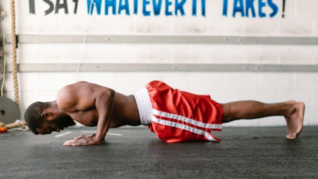Athletic man doing push-ups indoors with motivational text.