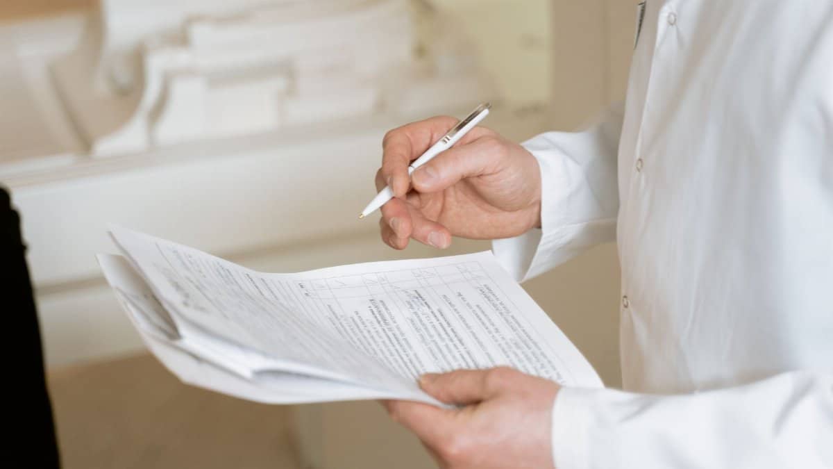 A doctor holds and reviews medical documents, demonstrating careful examination and professionalism.
