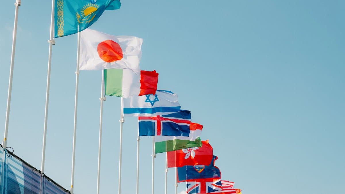 A row of international flags waving under a clear blue sky in Paris, France.