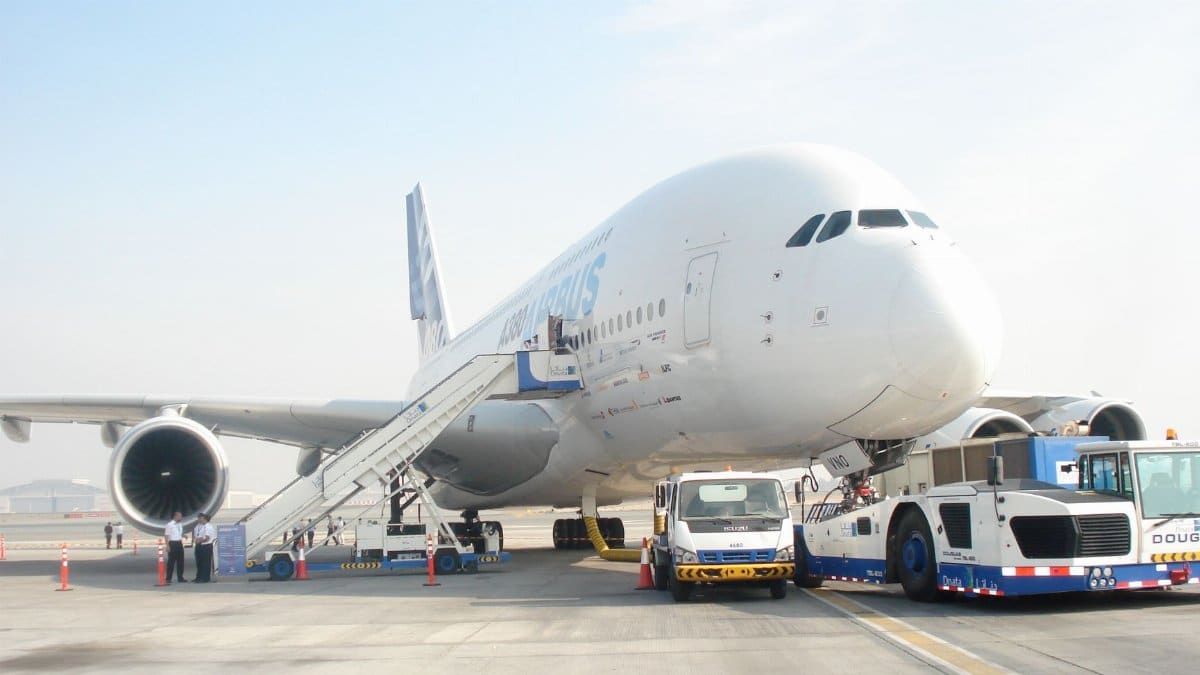 Huge commercial aircraft preparing for departure at airport with ground support vehicles.