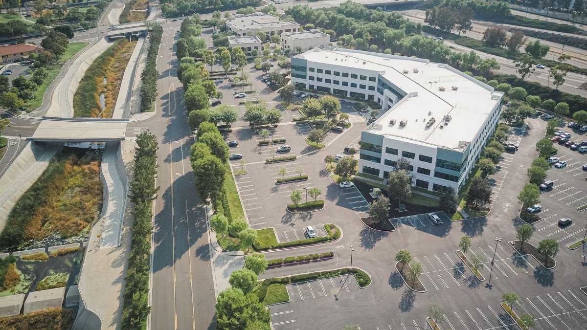 Aerial view of a suburban office building with empty parking lots and roads, captured in summer.