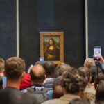 Tourists capturing the iconic Mona Lisa painting at the Louvre Museum.