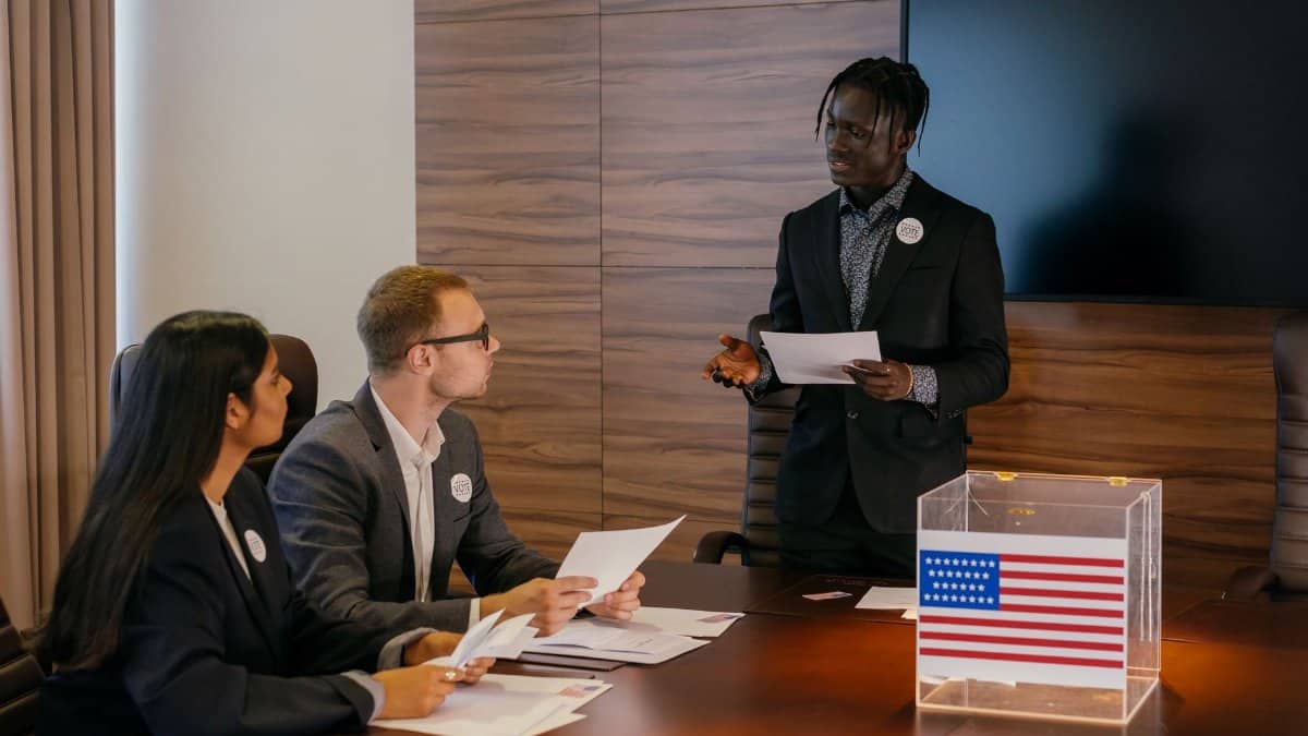Multiracial group of professionals engaged in a political meeting with a ballot box.