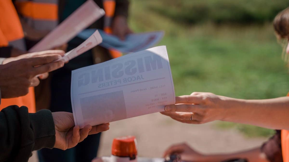 Group of volunteers handing out missing person flyers during a search operation outdoors.