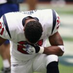 Football player in uniform kneeling before a game, displaying focus and determination.