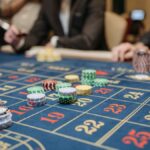 Hands placing betting chips on a roulette table in an upscale casino setting.