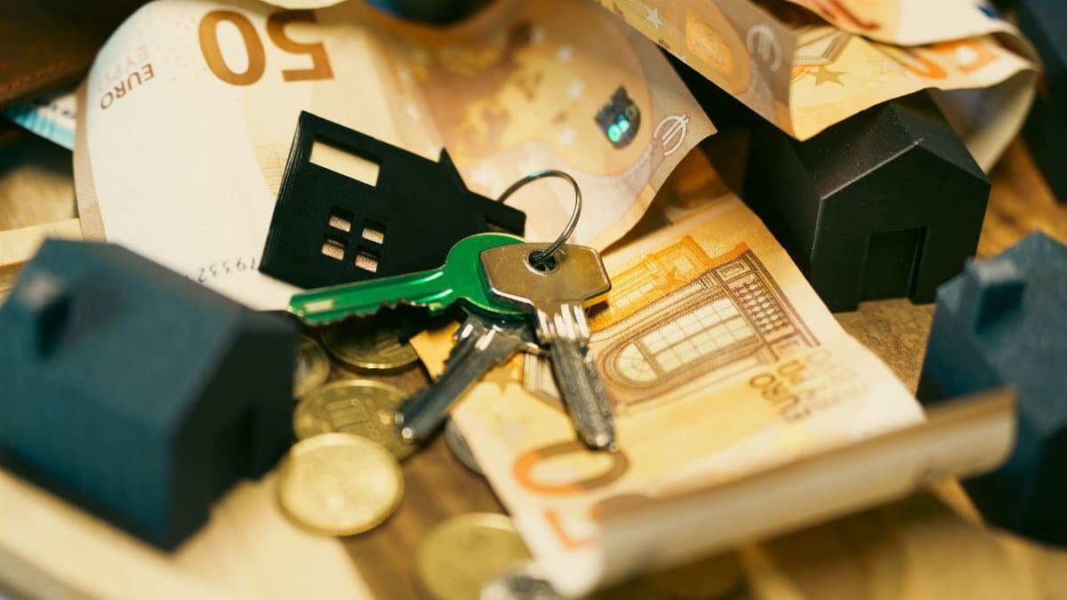 Euro currency with house keys and miniature models, symbolizing real estate investment.