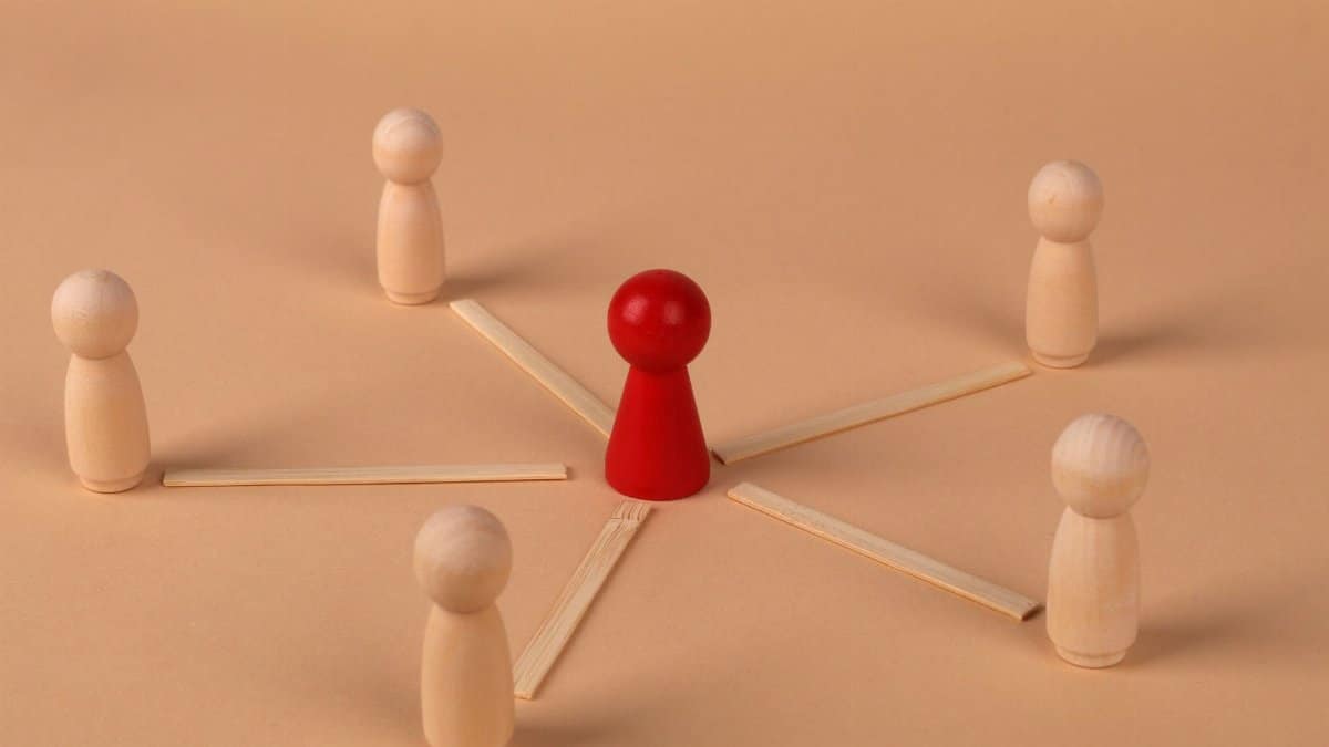 Wooden figures with red leader representing teamwork and influence.