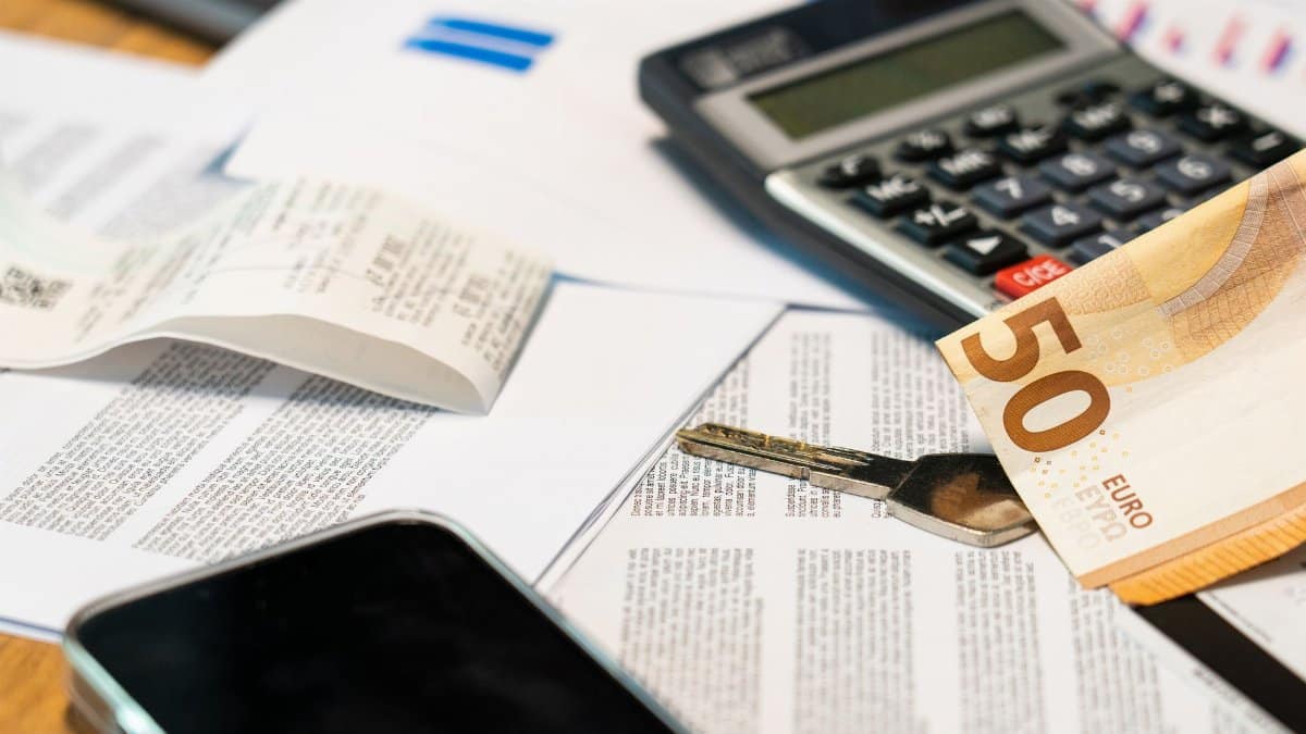 Flat lay of financial documents, euro note, calculator, smartphone, and key for budget management.