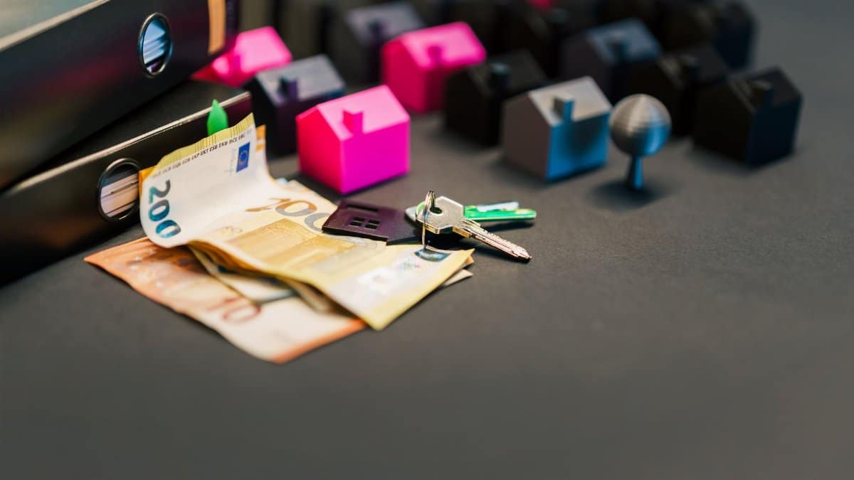 Miniature houses, euro bills, and a house key symbolize real estate investment and property transactions.