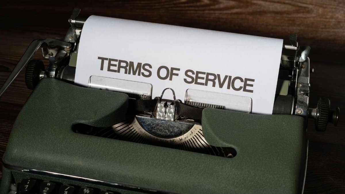 Close-up of a vintage typewriter with 'Terms of Service' paper inside, on a wooden desk.