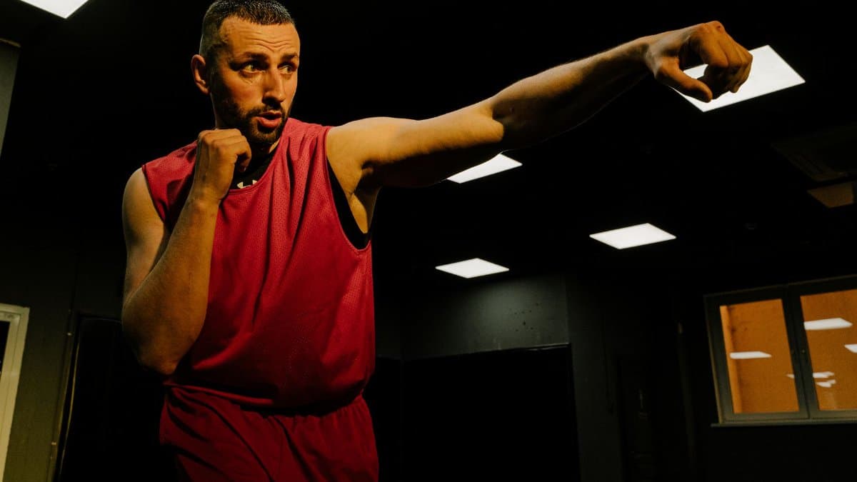 A man practicing punching techniques indoors in a gym, focused on fitness.