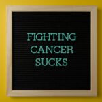 Inspirational message on a letter board raising cancer awareness against a vibrant yellow background.