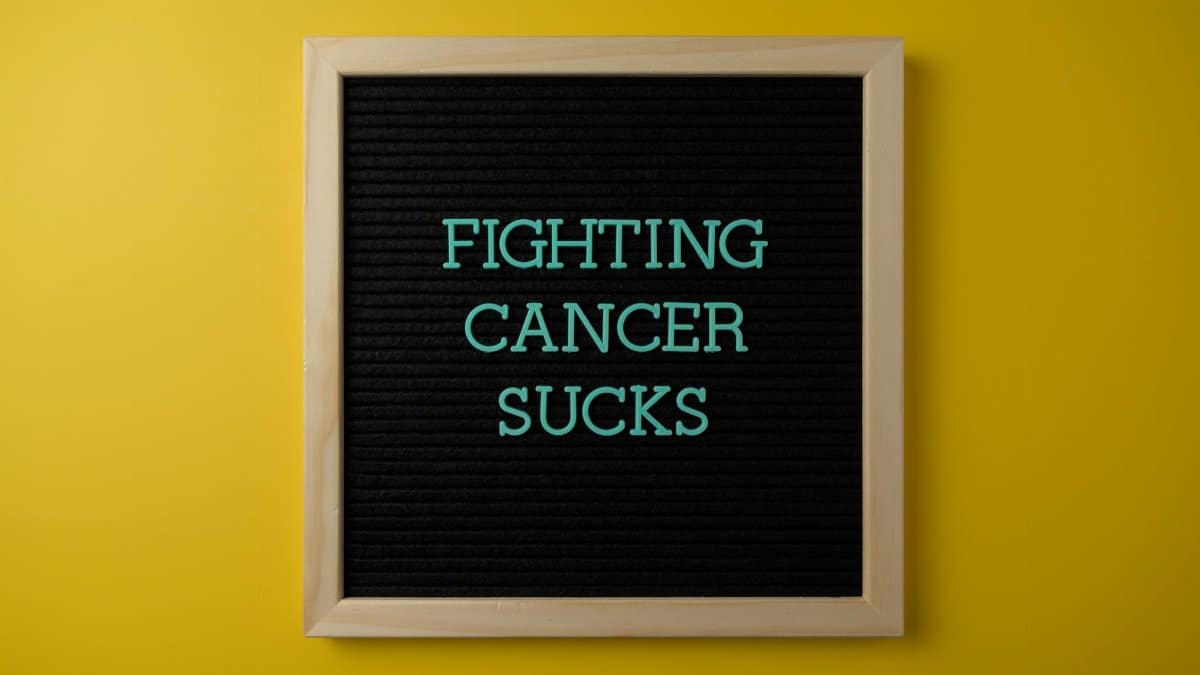 Inspirational message on a letter board raising cancer awareness against a vibrant yellow background.