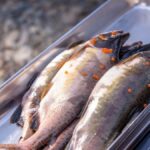 Raw salmon and trout with roe, placed on a digital scale outdoors, ideal for fisheries and culinary imagery.
