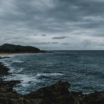 A dramatic view of Hawaiian coastline with storm clouds and rugged rocks.
