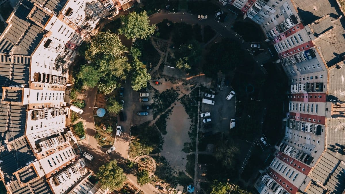 Stunning aerial shot of a circular residential complex surrounded by trees and open spaces.