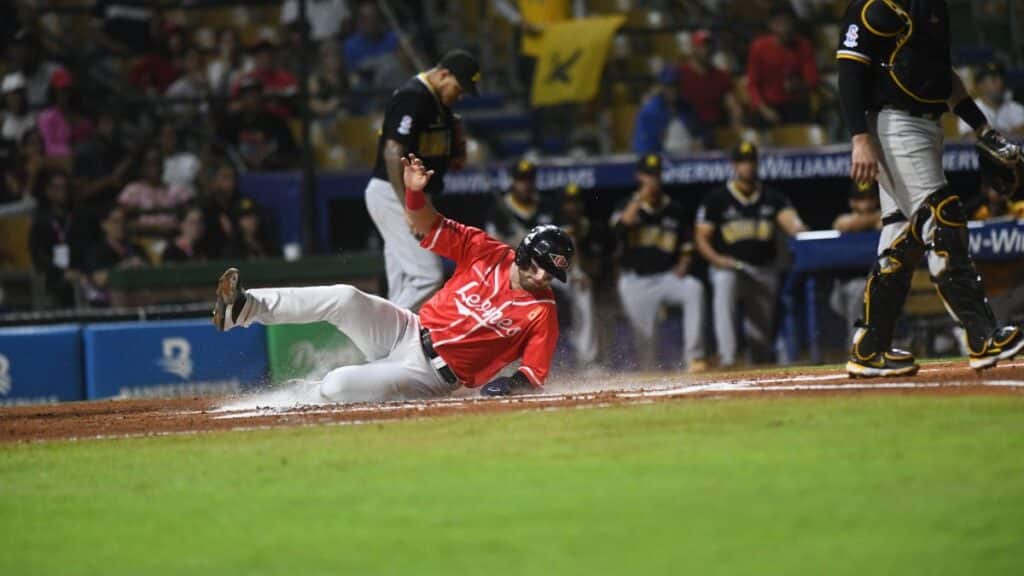 Sliding baseball player during an exciting game in Santo Domingo stadium.