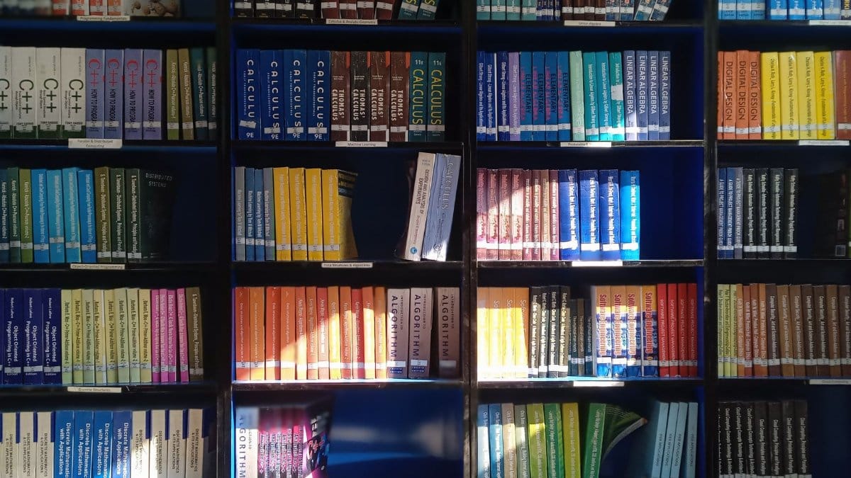 A vibrant library bookshelf displaying a range of educational books organized by subject.