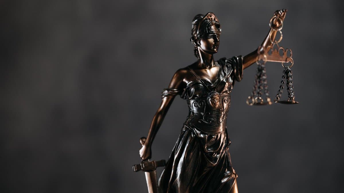 Detailed bronze Lady Justice statue with scales and sword against a dark background, symbolizing law and justice.