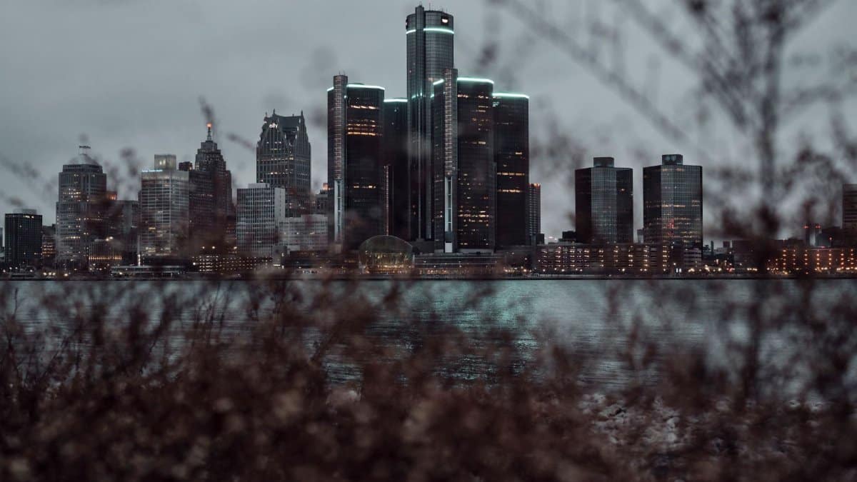 Dramatic view of the Detroit skyline across the waterfront at dusk, featuring skyscrapers.