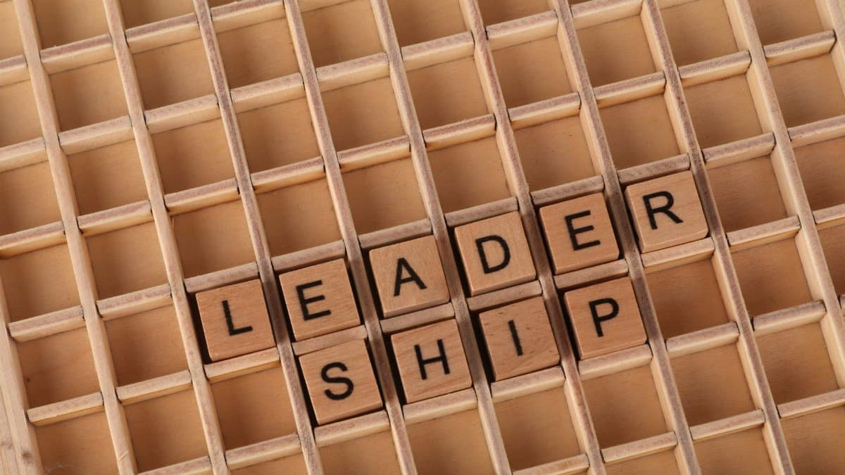 Wooden letter blocks spelling 'LEADERSHIP' on a grid background, emphasizing the leadership concept.