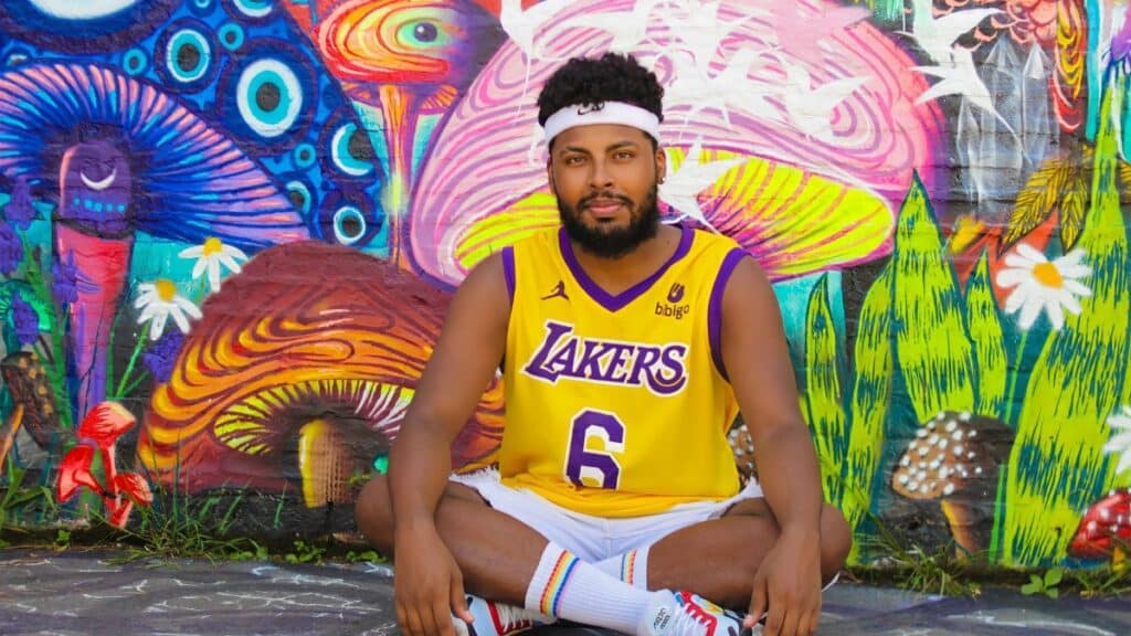 Man sitting against a vibrant mural wearing a Lakers jersey in São Paulo, Brazil.