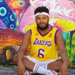 Man sitting against a vibrant mural wearing a Lakers jersey in São Paulo, Brazil.