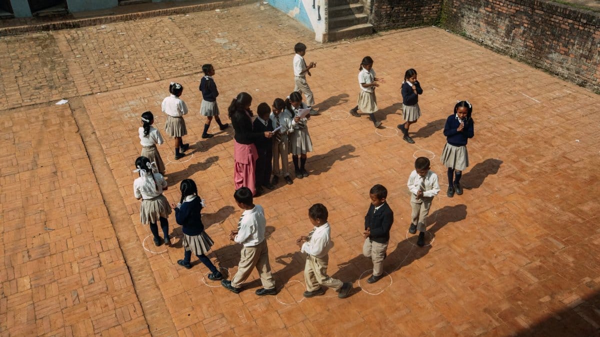 Aerial view of children playing a game on the school courtyard during daytime.