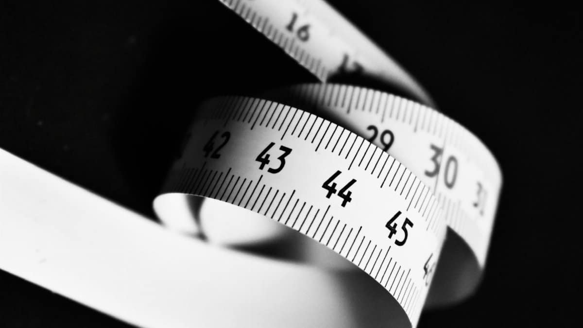 Curved white measuring tape with numbers 15 to 45 on a dark background.