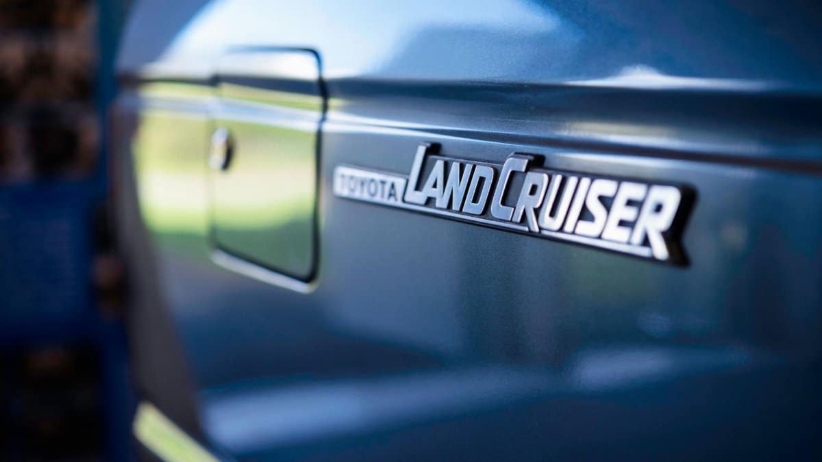 Detailed close-up of a Toyota Land Cruiser emblem on a blue vehicle, showcasing luxury and design.